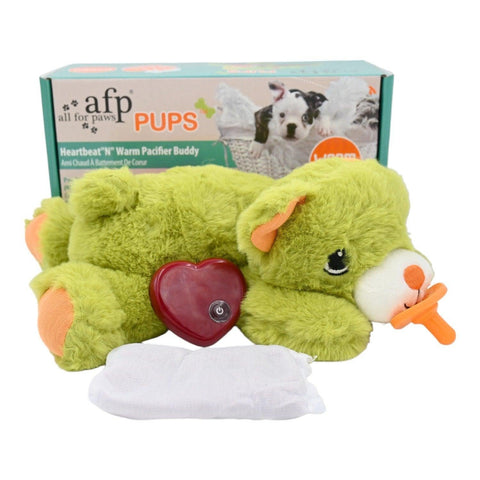 Pups Kalp Atışlı Peluş Emzikli Köpek Oyuncağı, yeşil ayıcık, kırmızı kalp ve ısıtıcı kese kutusunun önünde